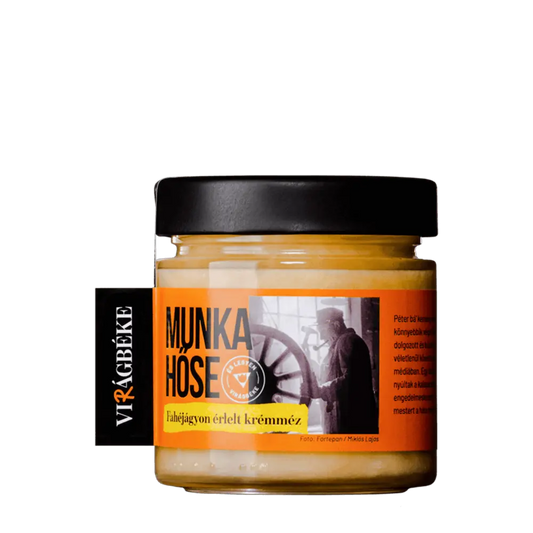 A Virágbéke "Munka hűse" fahéjágyon érlelt krémméze látható. A méz krém színű a címke narancssárga. Egy dolgozó embert lehet látni a képen. 
