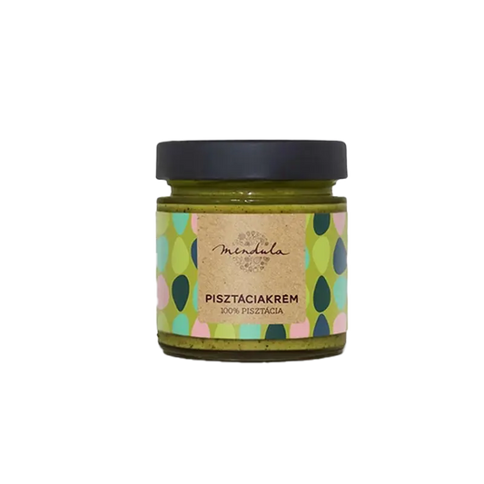 Mendula 100% pisztáciakrém, az üvegben látszik a szépen elkészített zöldszínű pisztáciakrém. A címkén zöld, világoszöld, sötétszöld és rózsaszín pötyök láthatóak, a címke alapszíne a világos zöld. A kupak színe fekete. 