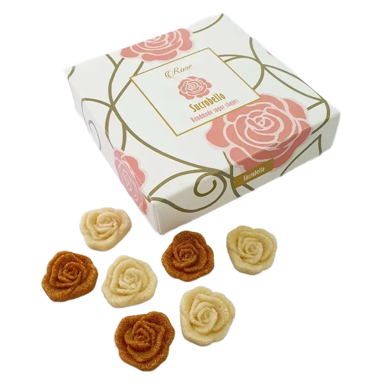 Zárt Sucrobello rózsa formacukor doboz látható, a dobozon két nagy rózsaszín rózsa van . A doboz előtt 6 darab (3 fehér, 3 barna) rózsa formacukor van elhelyezve. A díszdoboz esztétikus és tetszetős. 